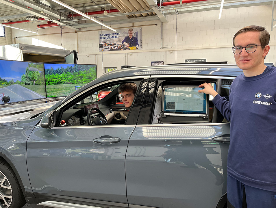 Bild 2: Die angehenden Kfz-Mechatroniker Jonas Stockinger (links) und Paul Schwientek (rechts) präsentieren einen zum Fahrsimulator umgebauten BMW X1.