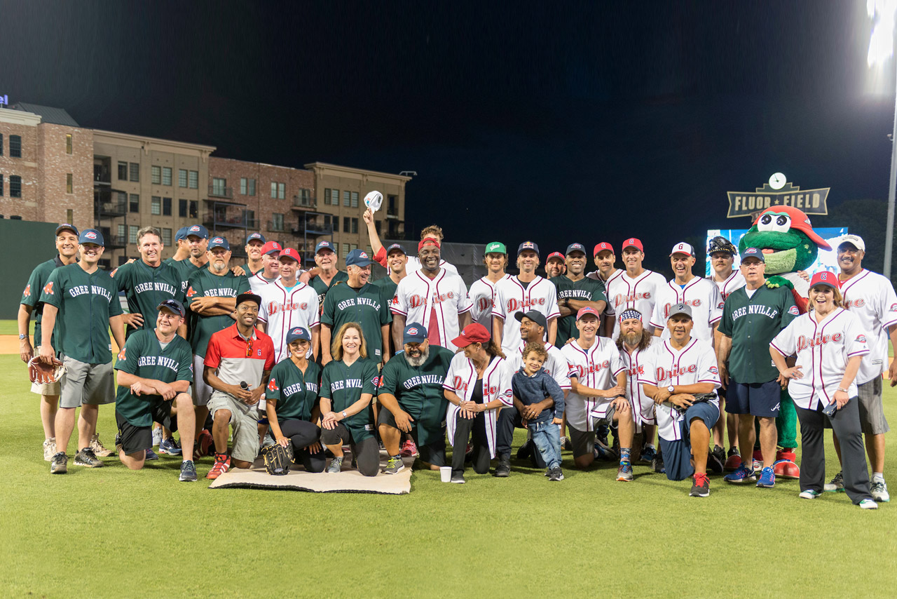 Players and Flour Field mascot line up for a night-time group shot. 