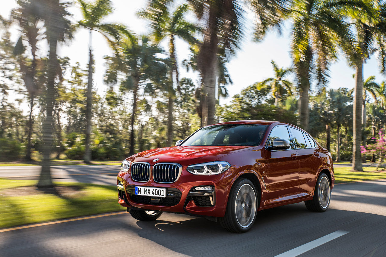 Gorgeous new BMW X5 being driven down a coastal highway surrounded by palm trees. 