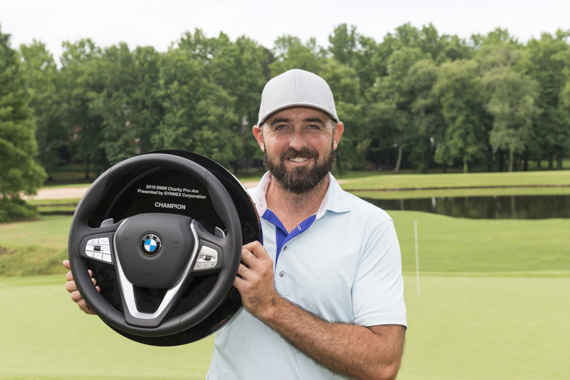 Rhein Gibson, 2019 winner,  holds up steering wheel award on 18th hole at Thornblade Club. 